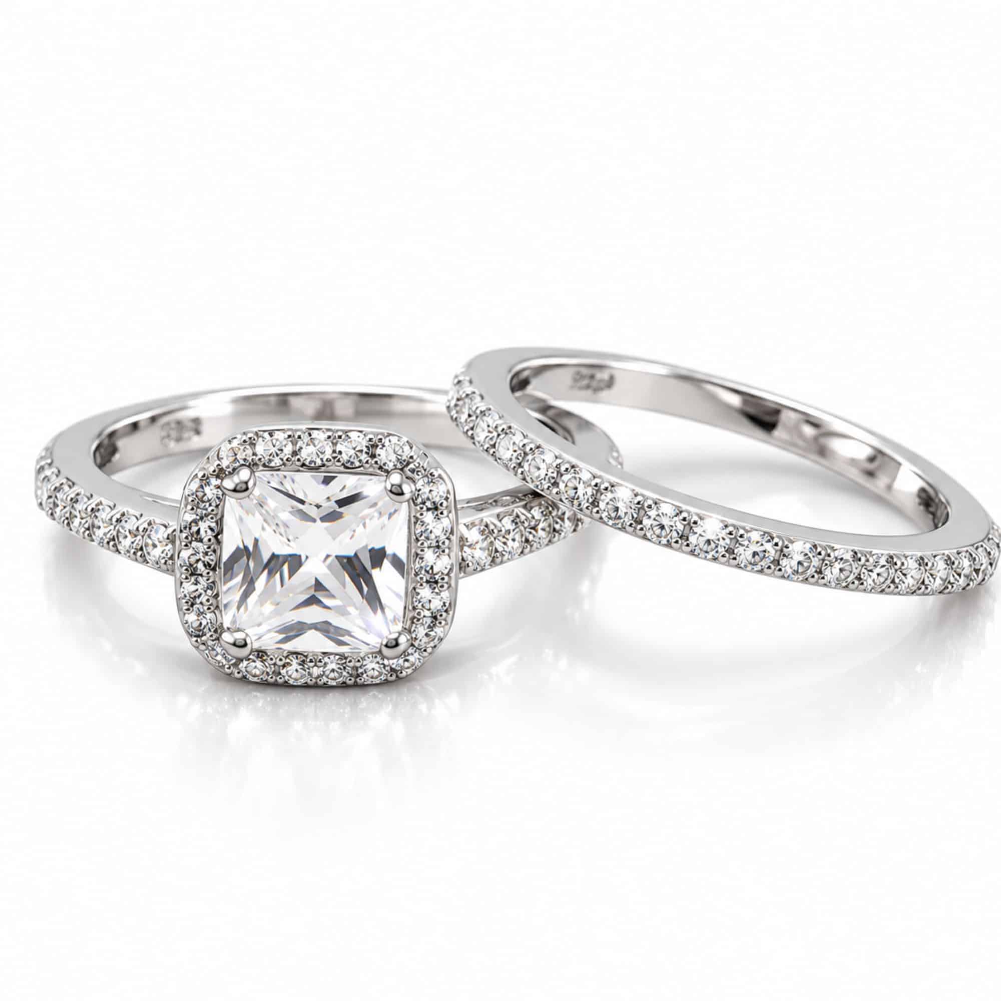 Silver-tone two-ring bridal set with square clear CZ center, halo accents and matching CZ wedding band.
