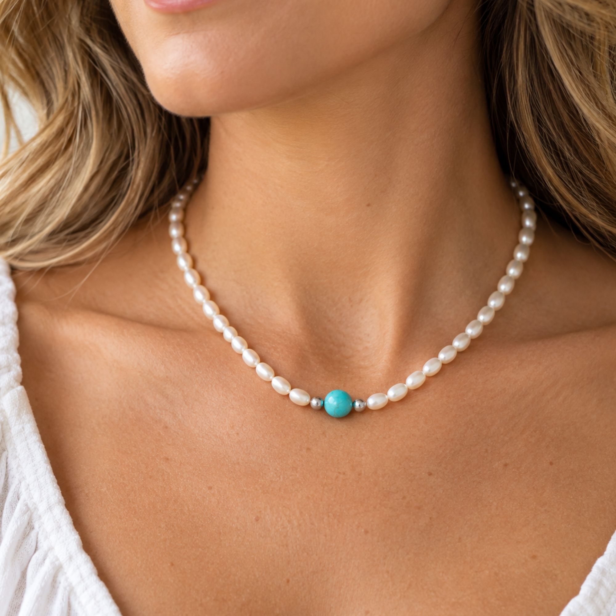 White cultured freshwater pearl necklace with a single turquoise center bead and small silver accent beads.