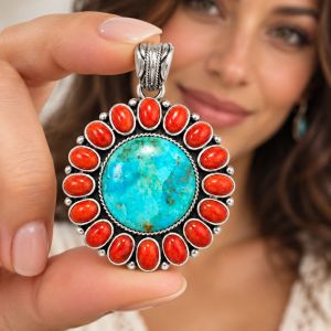 Oxidized silver sunburst pendant with a large oval turquoise center surrounded by orange coral stones.