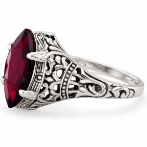 Oxidized sterling silver ring with a large faceted marquise garnet and ornate openwork detailing on the shoulders.